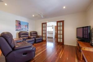 a living room with leather furniture and a flat screen tv at Your Home at Southside Central - Family friendly. in Bundaberg