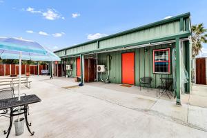 a green building with a table and an umbrella at Casas Coastal Experience Cabin A in Rockport