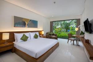 a bedroom with a bed and a large window at Taksu Sanur Hotel in Sanur