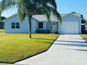 una palmera frente a una casa azul en Home Away From Home en Vero Beach