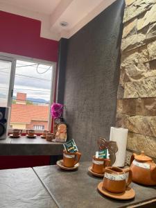 a table with cups of coffee and a stone wall at Farolito de Luz Apart in Salta