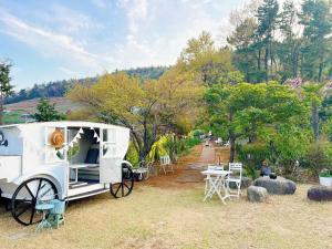 a white trailer parked in a field with tables and chairs at Country House Exclamation Mark & Comma in Namhae