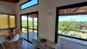 a room with a table and chairs and large windows at Mansavista Cabañas in Potrero de Garay