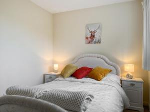 Un dormitorio con una cama blanca con almohadas rojas y amarillas en Rosings, en Bradfield