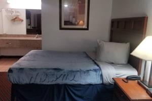 a bedroom with a bed and a bathroom with a sink at OSU Queen Bed Hotel Room 117 Wi-Fi in Stillwater
