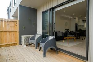 a patio with two chairs and a table and a room at Modern Howick Town House Fibre WiFi Netflix in Auckland