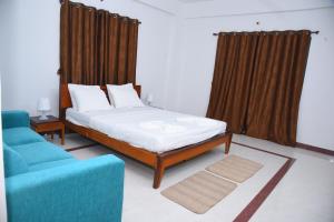 ein Schlafzimmer mit einem Bett und einem blauen Sofa in der Unterkunft Hotel Solis Stay in Solapur