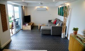 3 Waters Guest Accommodation في غولد كوست: غرفة معيشة مع أريكة وتلفزيون