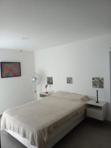Un dormitorio blanco con una cama y dos mesitas de noche. en Takú Huasi, en La Rioja