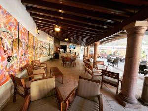 un restaurante con sillas, mesas y pinturas en la pared en Hotel Hacienda Ventana del Cielo, en Tepoztlán