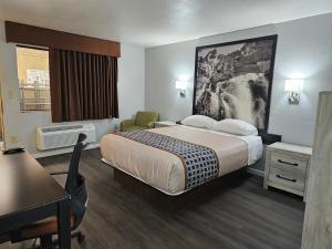 a small hotel room with a bed and a desk at Canyon Inn Flagstaff in Flagstaff