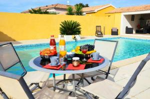 una mesa con comida y bebida junto a una piscina en Résidence MARI, en Folelli