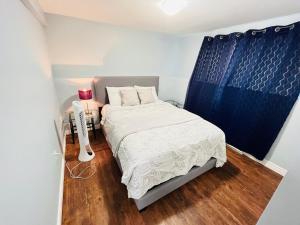 a small bedroom with a bed and a blue curtain at Basement unit with 2 bedrooms, bath and living area in Lower Sackville