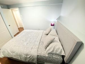 um pequeno quarto com uma cama com um edredão branco em Basement unit with 2 bedrooms, bath and living area em Lower Sackville