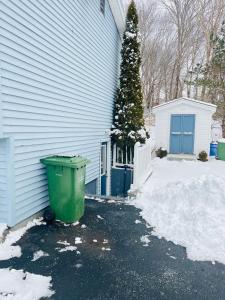 a green trash can sitting next to a house at Basement unit with 2 bedrooms, bath and living area in Lower Sackville