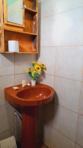 ein Badezimmer mit einem hölzernen Waschbecken mit Blumen darauf in der Unterkunft Hostel Loli in Puerto Iguazú