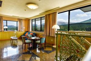 Habitación de hotel con mesa, sillas y ventanas en Hotel Aso No Tsukasa, en Aso