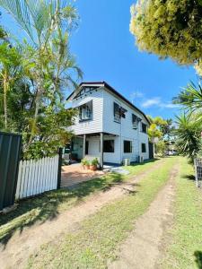 a white house with a fence next to a yard at Spacious 5 BR Family Home with free WIFI & AC pet friendly in Bundaberg