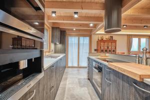 a large kitchen with wooden ceilings and wooden counters at Chalet Capucchione in Les Diablerets