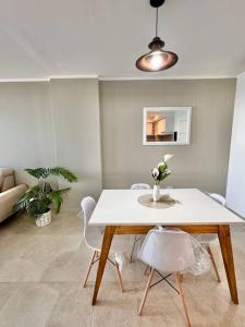 einen Tisch und Stühle im Wohnzimmer mit einer Blumenvase in der Unterkunft PISO 12 Edif Alarif Trench in Posadas