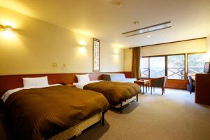 阿蘇市にあるHotel Aso No Tsukasaのベッド2台とデスクが備わるホテルルームです。