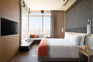 um quarto de hotel com uma cama, um sofá e uma televisão em Jumeirah Guangzhou em Guangzhou