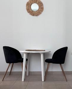 una mesa blanca con 2 sillas y un espejo en Casa by Hokkum Studios, en Kokkari