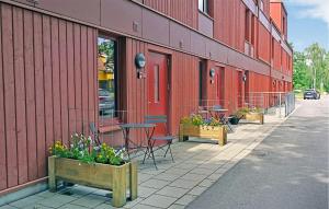 un edificio rojo con mesas, sillas y flores en la acera en Cozy Apartment In Frjestaden With Wifi, en Färjestaden