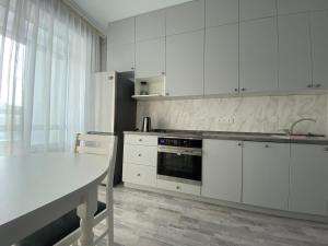 a kitchen with white cabinets and a white table at Sati Club House in Prigorodnyy