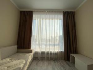 a bedroom with a bed and a large window at Sati Club House in Prigorodnyy