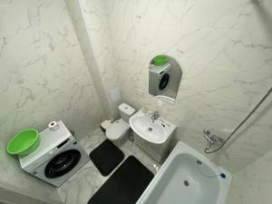 a white bathroom with a toilet and a sink at Sati Club House in Prigorodnyy
