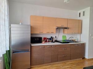 a kitchen with wooden cabinets and a stainless steel refrigerator at Apartament Rose Stalowa Wola in Stalowa Wola