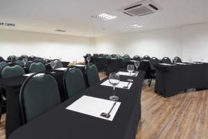 una sala de conferencias con mesas negras y sillas con copas de vino en Intercity Salvador Aeroporto, en Lauro de Freitas