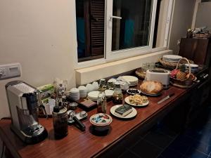 a table with food and a coffee maker on it at La maison bleue BTB in Phumĭ Kâmpóng Âmpĭl