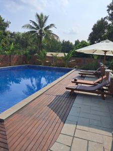una piscina con 2 tumbonas y una sombrilla en La maison bleue BTB, en Phumĭ Kâmpóng Âmpĭl