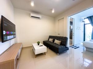 a living room with a black couch and a tv at Downtown Remin Suites at The Shore Kota Kinabalu in Kota Kinabalu