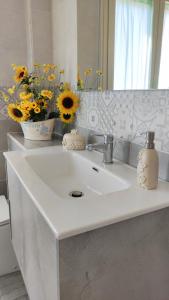 lavabo con jarrón de flores y espejo en Capitan Shonny, en Portoscuso