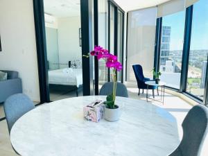 una mesa blanca con una flor púrpura en una habitación con ventanas en Fascinating waterview 2 bedrooms condo (Parking), en Sídney