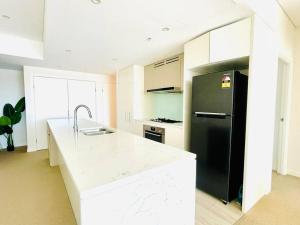 cocina con nevera negra y encimera blanca en Fascinating waterview 2 bedrooms condo (Parking), en Sídney