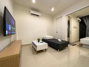 a living room with a black couch and a flat screen tv at Downtown Remin Suites at The Shore Kota Kinabalu in Kota Kinabalu