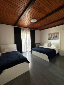 a bedroom with two beds and a wooden ceiling at Apartments Vukovic in Selce