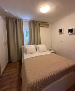 a bedroom with a bed with white sheets and a window at Apartments Vukovic in Selce