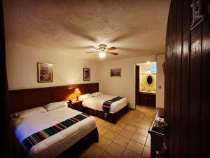 Habitación de hotel con 2 camas y ventilador de techo. en Hotel Hacienda Ventana del Cielo, en Tepoztlán