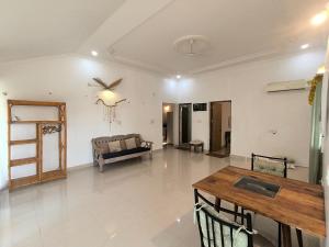 uma sala de estar com uma mesa e um sofá em Apartments close to Thalassa em Siolim