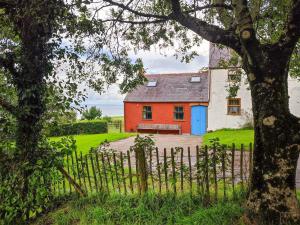 una casa roja y blanca con una puerta azul en Ceiliog Bach, en Llangennith