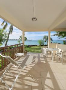 eine Veranda mit Stühlen, Tischen und Meerblick in der Unterkunft LAGOON VIEW Résidence in Grand Baie