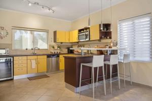 a kitchen with yellow cabinets and white bar stools at Splendid 3 bedroom house with beauttiful pool in Noord