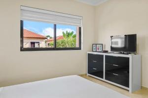 a bedroom with a bed and a tv and a window at Splendid 3 bedroom house with beauttiful pool in Noord