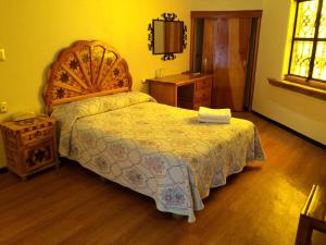 a bedroom with a large bed with a wooden headboard at Hotel Estelar in Taxco de Alarcón
