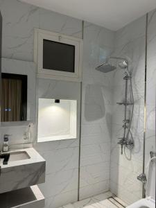 a bathroom with a shower and a sink and a television at Crown Al-Ula in AlUla